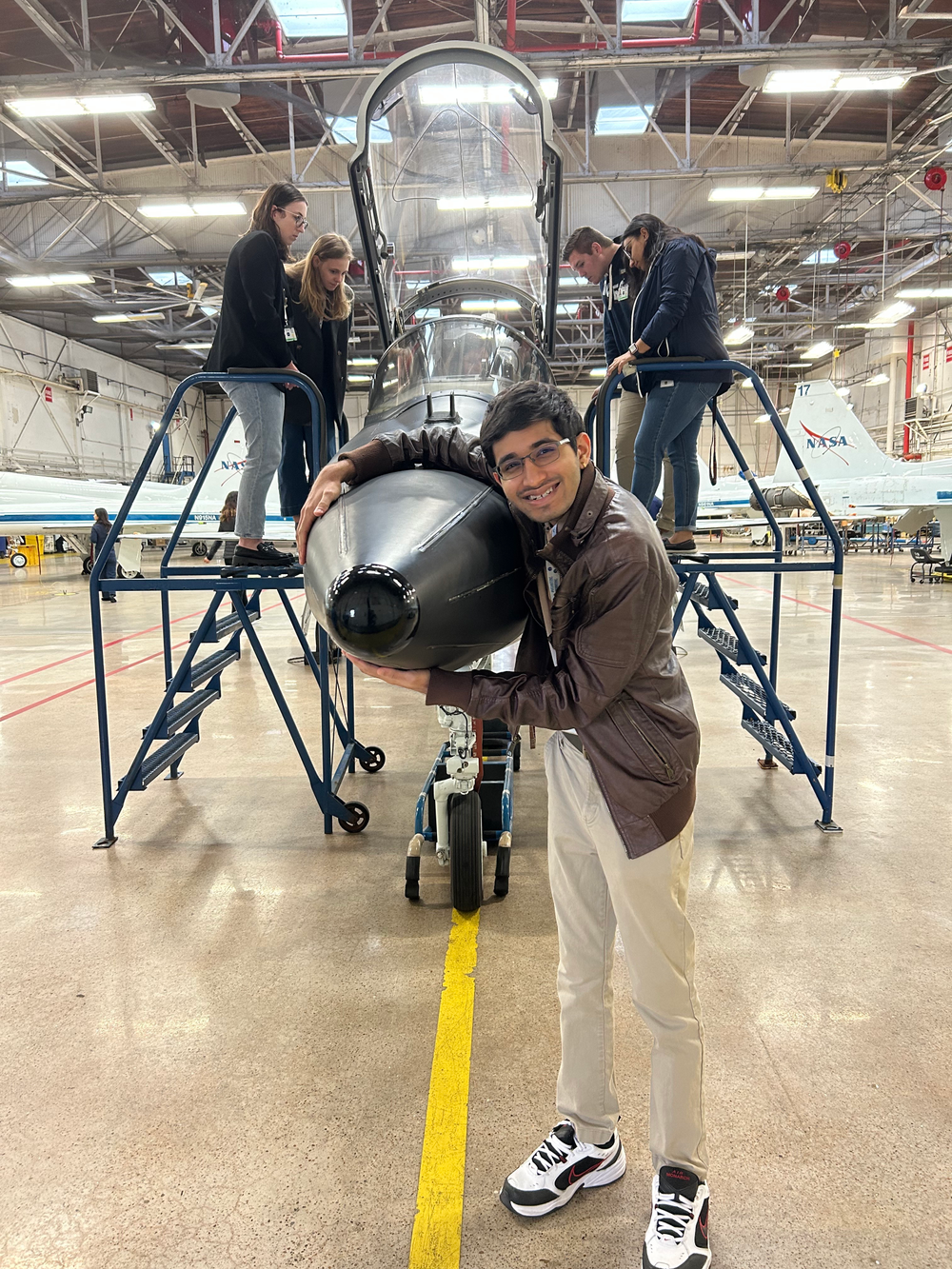 Raj Gohil on a tour of the Ellington Field Hangar in Houston, Texas posing with a T-38 plane.